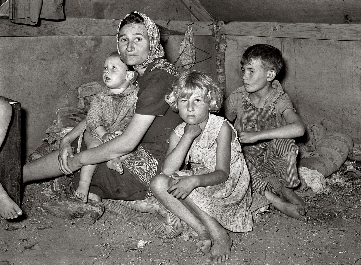 February 1939. "White mother with children at migrant camp. Weslaco, Texas." Background for this series of photos as recorded by Russell Lee in his notes: "Local employment men say that there was no need for migrant labor to handle the citrus and vegetable crops in the valley, the local supply of labor being ample for this purpose. Most of the local labor is Mexican and the labor contractors favor Mexican labor over white labor, partly because the Mexican will work much cheaper than whites. One white woman who was a permanent resident said that the white people who lived in the valley had no trouble with the Mexicans. The Mexicans were good neighbors, she said, always willing to share what they had. She said the white migrants who came into the valley and resented and misunderstood the Mexicans caused the trouble between the two races. Some towns in this section permit camping only in trailers. The charge for camping in tents is about fifty cents per week, including water, which in some cases must be carried four city blocks. Privies are tin, very bad condition. Garbage is collected only once a week, with large dumps of decaying fruits and vegetables scattered among the camps. Some of the white migrants in this camp were very suspicious of governmental activity, due to the use by south Texas newspapers of the term 'concentration camps' referring to Farm Security Administration camps." Medium format nitrate negative by Russell Lee for the FSA. View full size.
