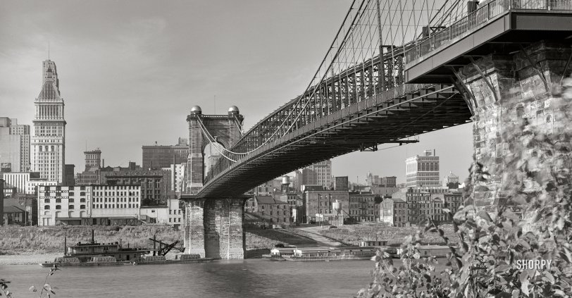 Spring 1941. "View under Roebling Suspension Bridge of Cincinnati from Kentucky side of the Ohio River. Waterfront showing numerous business houses: Colter Grocers, Cincinnati Grain &amp; Hay, King Bag, Queen City Rag &amp; Paper and others." 4x5 inch acetate negative. View full size.
