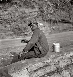 September 1938. Capels, West Virginia. "Coal miner waiting for lift home." Medium-format nitrate negative by Marion Post Wolcott. View full size.
Sixteen tonsIf I seen him comin', I'd step aside.
LavaWere these men ever really able to clean up. I imagine after a while the grime just became part of the whole.
And a smoker too.God that job must have sucked.
Black Lung a&#039;cominCoal dust and Tobacco smoke, great for the lungs. I would have thought just having the sunshine on your face and fresh air would be reward enough after a hard day's work.
Coal Miner&#039;s GranddaughterMy grandfather (papaw to the grandkids) was a coal miner in Harlan County, KY during the '30s and '40s.  I remember my mom telling me that he never came home w/ coal dust on him; he always made sure to wash up before leaving work.  I knew him only after his coal mining days.  Even after he was retired, he would take a long shower, shave, and shine his shoes every day.  He was meticulous.
The tough life of a coal minerMy family comes from the coal country of SW Pennsylvania.  As a young kid I remember my coal miner grandpa as a worn-out old man with black lung and (later) cancer of the esophagus -- even though he couldn't have been older than his late 50s.  
Visiting with my uncles recently, both well into their 80s, I learned more from them about just how tough it was to be a miner back in the '30s and '40s.  One particular story sticks.  During a very cold winter's day my granddad emerged from the mine soaked in his sweat and walked the five miles home, arriving with his clothes frozen stiff.  He ordered one of my uncles to walk to a local store to buy a pint of vodka, which he drank before going to bed.
Apparently that was a common way for him to end his day.
(The Gallery, M.P. Wolcott, Mining)