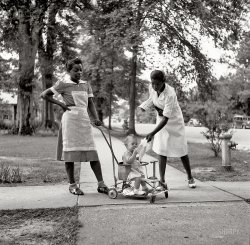 August 1940. "Port Gibson, Mississippi." Medium-format nitrate negative by Marion Post Wolcott for the Farm Security Administration. View full size.
Ms. MaybellineJust finished reading "The Help" -- a portrait straight from the book. Nurse and maid? They must be pretty far from the house, the maid has got those hot scratchy hose rolled all the way down to her ankles.
Street ViewSo much that is interesting in this picture -- the pushcart stroller, the saddle oxfords, and the unique apron, which must have been pinned to the girl's bodice, since it has no ties. A perfect slice-of-life picture.
Junior&#039;s buggyThey are called Taylor Tiny Tots. Four swivel wheels, a push handle that can be removed, and a custom owner operated steering wheel. When Junior gets older, you remove the steel belly pan and the handle, and he can operate it by himself. A smart invention.
Apron ChicAll good aprons are pinned. Straps are for scullery maids and butchers.
Marion Post Wolcott FanMarion had the eye of an artist and the mind of a scholar.  She's packed a lot of history into a deceptively simple image.  It's a trick that she pulled off time and again.  Click on her name above the photo for more. You'll see what I mean.
Taylor Tiny TotsDon't know for sure if that is what I had when I was under 2 years old -- born in 1942. Mine was a light blue color and may have had some modifications due to the war effort.  I know my first tricycle had no rubber on the wheels because of materials needed in World War II.
Toe-TiedMy stroller (late '40s) was very similar. My father told me that once when he took me to the grocery store, the owner commented on how well behaved I was, compared to when I was with my mom: "When he's with your wife, he's out of that stroller and into everything." That's because my dad tied my shoelaces together.
Family pictureThis picture is my dad. We have this picture in my dad's things. It was taken in front of my grandparents house. I have seen it other places and have seen that it is the cover of the UK version of the help. My question is, how did it get out there? We don't mind just have always wondered. Any help would be great. - thanks!
[The photo was taken for the Farm Security Administration, a U.S. Government agency. Their files and photographs are archived at the Library of Congress, and are in the public domain. The record and high-resolution scan of this particular negative can be found at the LOC via this link. -tterrace]
(The Gallery, Kids, M.P. Wolcott)