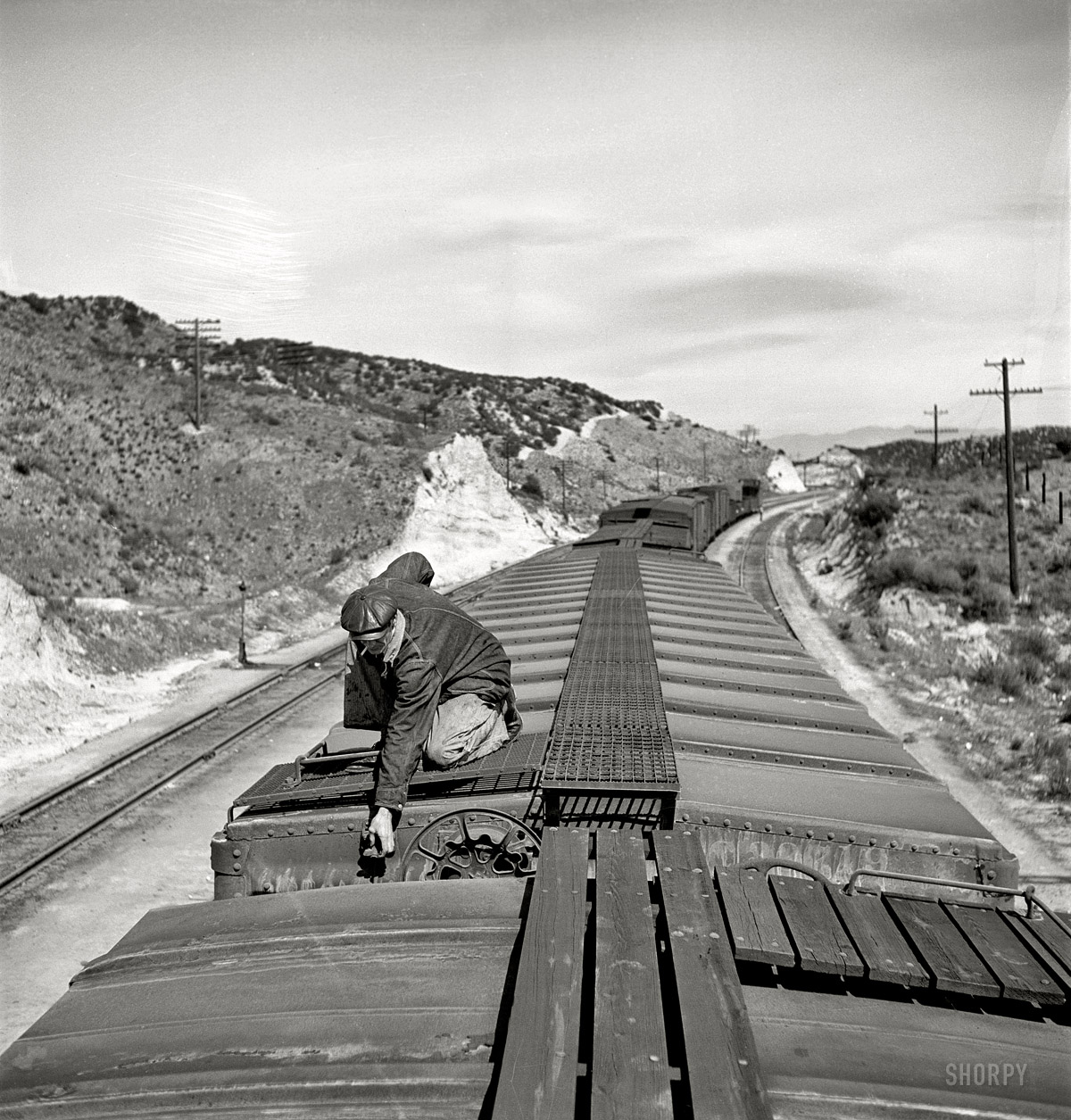March 1943. Summit, California. "Brakeman opening the retainer valve on a car on the Atchison, Topeka and Santa Fe Railroad between Barstow and San Bernardino. From here to San Bernardino is one long downgrade of more than 2,700 feet." Photo by Jack Delano, Office of War Information. View full size.