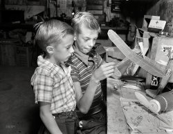September 1942. Rochester, New York. "Earl and Howard Babcock looking over one of the model airplanes which Howard built." The boys seems to have migrated from the bedroom to the basement. Photo by Ralph Amdursky. View full size.