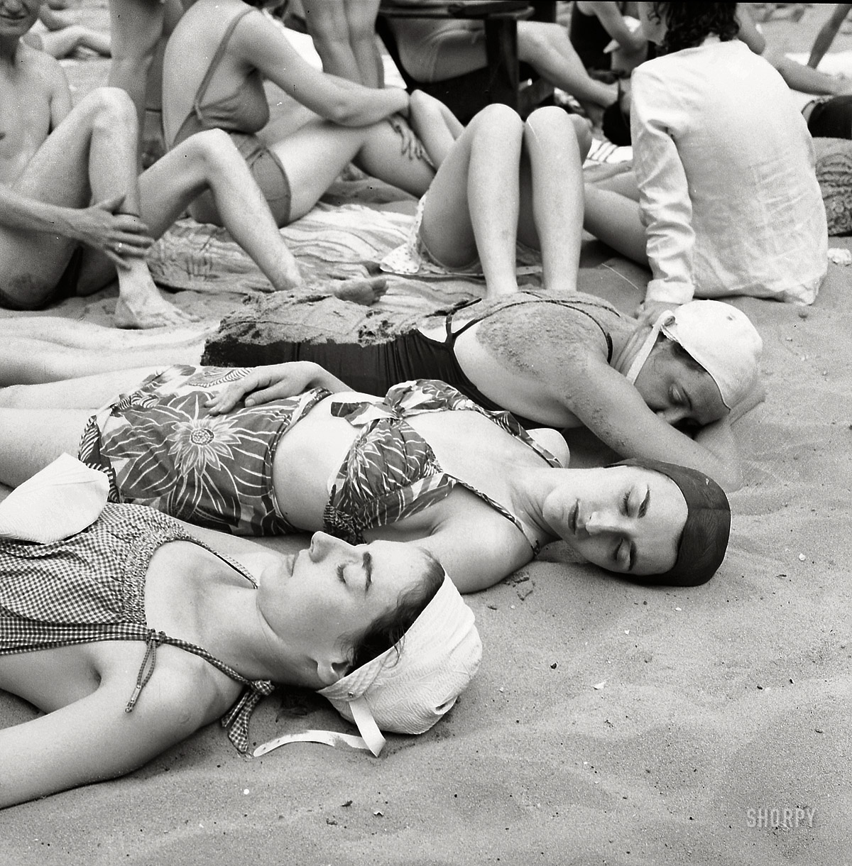 July 1943. Glen Echo, Maryland. "Sun bathers on the sand beach at the swimming pool in the Glen Echo amusement park." In the foreground: The photographer's sisters Claire and Enid Bubley. Photo by Esther Bubley, OWI. View full size.