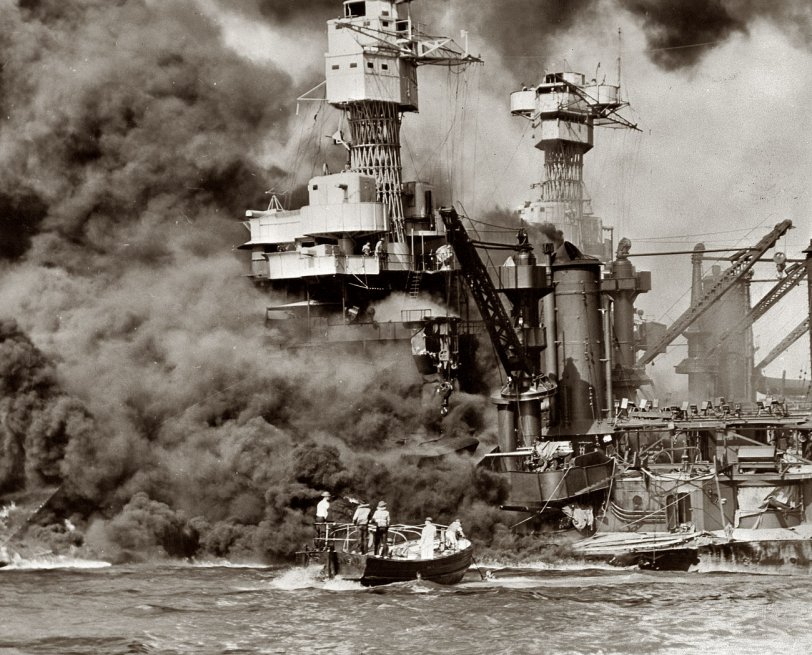 December 7, 1941. Pearl Harbor, Hawaii. Small boat rescues a seaman from the 31,800-ton USS West Virginia. Note the two men in the superstructure. The USS Tennessee is inboard. View full size. Office of War Information.
