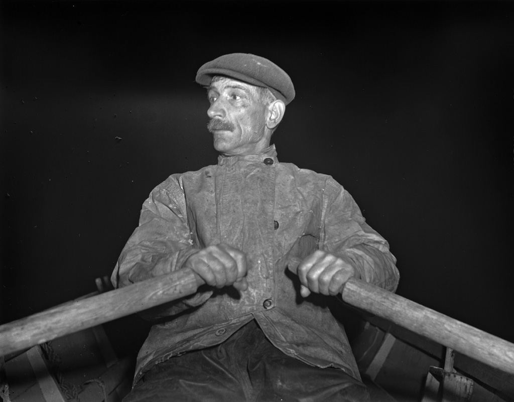 A Portuguese dory fisherman rows his boat out at 4:30 a.m. leave for the banks off Cape Cod. Photograph by John Collier, 1942. View full size.