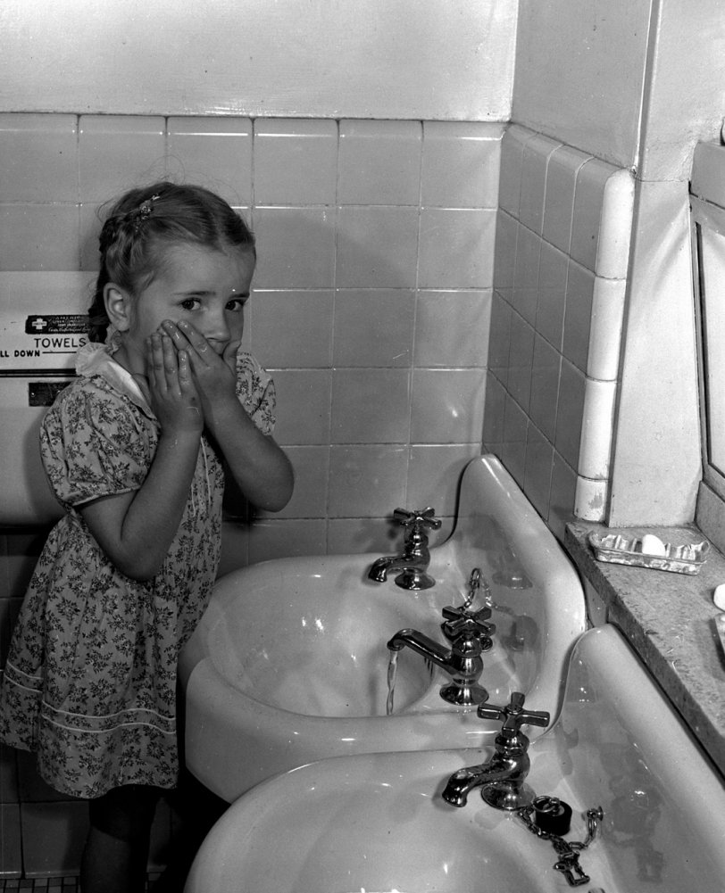 Photo of: A Little Privacy, Please II -- A child washes before lunch at the nursery school at the Queensbridge housing project in Queens, New York. Photograph by Arthur Rothstein, June, 1942. View full size.