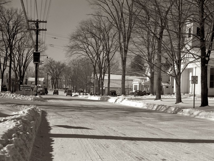January 1942. Bantam, Connecticut. The business section of Bantam with the camera facing south along Lafayette Boulevard (Route 25). A few rods to the left is the Warren McArthur plant [fabricator of aluminum aircraft parts], while the block of stores visible at the left includes Mitchell's Tavern, the First National Store, a garage and two service stations. Not shown, but lying just this side of Mitchell's restaurant, is the birthplace of Horace Bushnell, a discoverer of anaesthesia. Reading from the right are the Episcopal Church, Tony's Bantam Inn (favorite eating place), Marcel Roy's drugstore, the Bantam grocery store and the firehouse. View full size. Photo and caption by Howard Hollem for the OWI.
