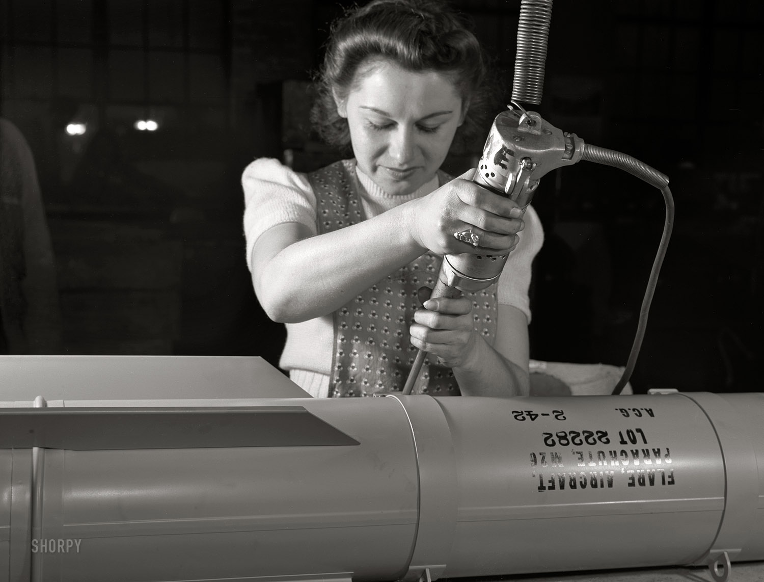 February 1942.  A.C. Gilbert Company, New Haven, Connecticut. "Conversion. Toy factory. Stephanie Cewe's skill with this electric screwdriver has been turned to the aid of Uncle Sam's war machine. Stephanie used to assemble toy locomotives; today, she uses the same screwdriver to assemble parachute flare casings." Photo by Howard Hollem, Office of War Information. View full size.