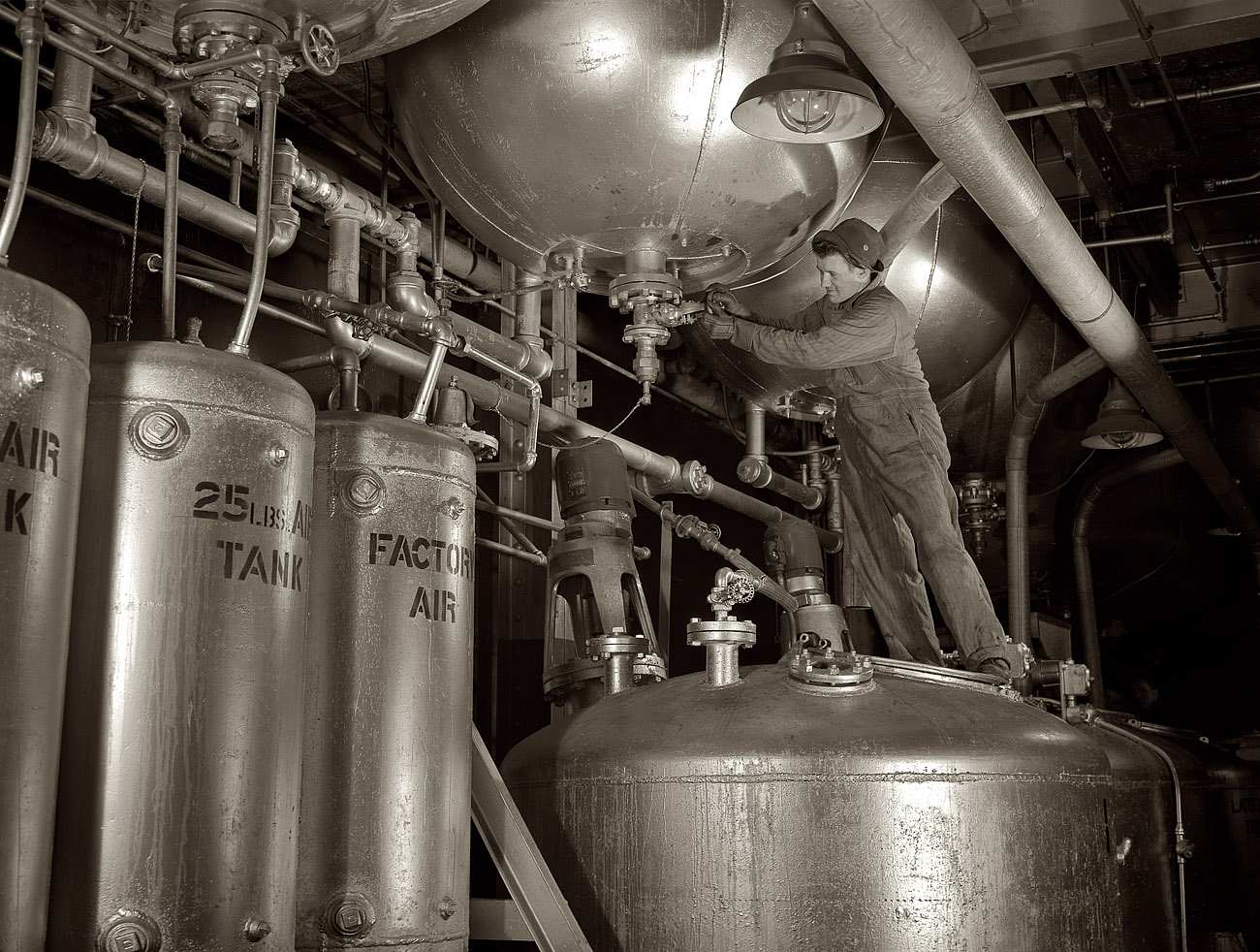 February 1942. "Synthetic rubber (Ameripol). Worker standing on blowdown tank, ready to tap polymerizer tank at the Akron, Ohio, synthetic rubber plant of the B.F. Goodrich Co." View full size. 4x5 nitrate negative by Alfred Palmer.
