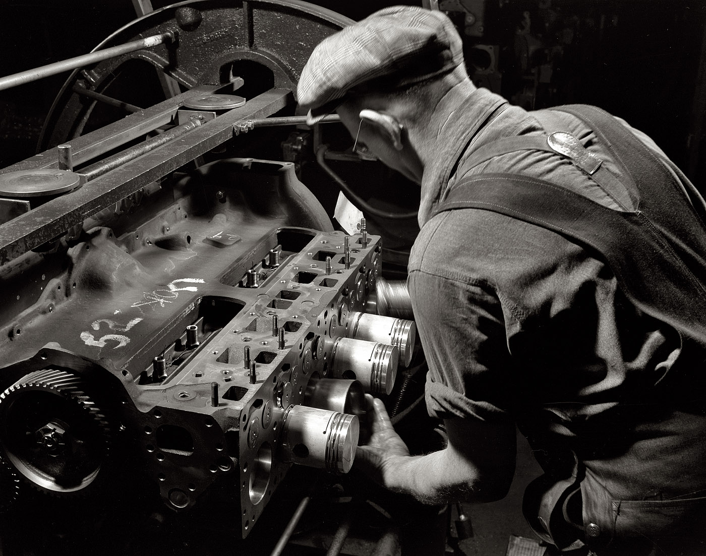 Another selection from the LOC archives of Alfred Palmer's strikingly composed large-format black-and-white transparencies shot in December 1941 at factories in Akron and Cleveland. White Motor Company, Cleveland, Ohio. "Halftrac scout cars. Putting precision-made pistons assemblies into precision-made cylinders is a job that fits this former auto worker. The engine will be the power plant of an Army halftrac scout car. The Midwest plant that is turning it out has trained American automotive workers for every job on the line." View full size. 4x5 nitrate negative by Alfred Palmer for the Office of War Information.