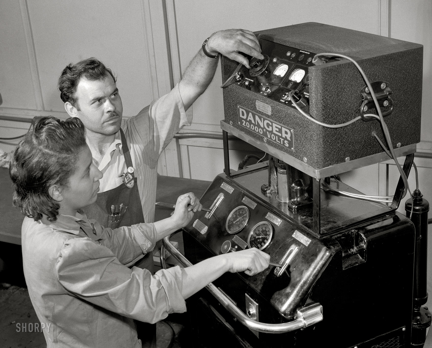 July 1942. Melrose Park, Illinois. "Production of aircraft engines. Buick plant. Foreman F.I. Bowman shows Marietta Morgan how to operate this bomb-test machine used to test reconditioned spark plugs. A young Negro girl, Marietta had been a clerk in a meat market. Her lack of industrial experience, however, has been no handicap for her present war job in a large Midwest airplane plant. She's rapidly becoming a skilled and efficient machine operator." Medium format safety negative by Ann Rosener for the Office of War Information. View full size.