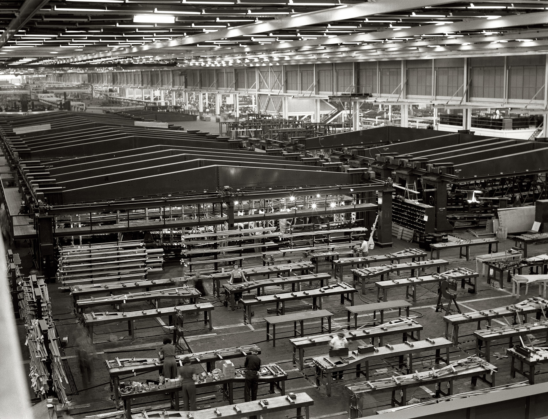 July 1942. "Willow Run bomber plant. A small part of the world's largest one- story war production plant, the giant Ford bomber factory at Willow Run, Michigan. Fixtures in background hold bomber wings during assembly." Photograph by Ann Rosener for the Office of War Information. View full size.