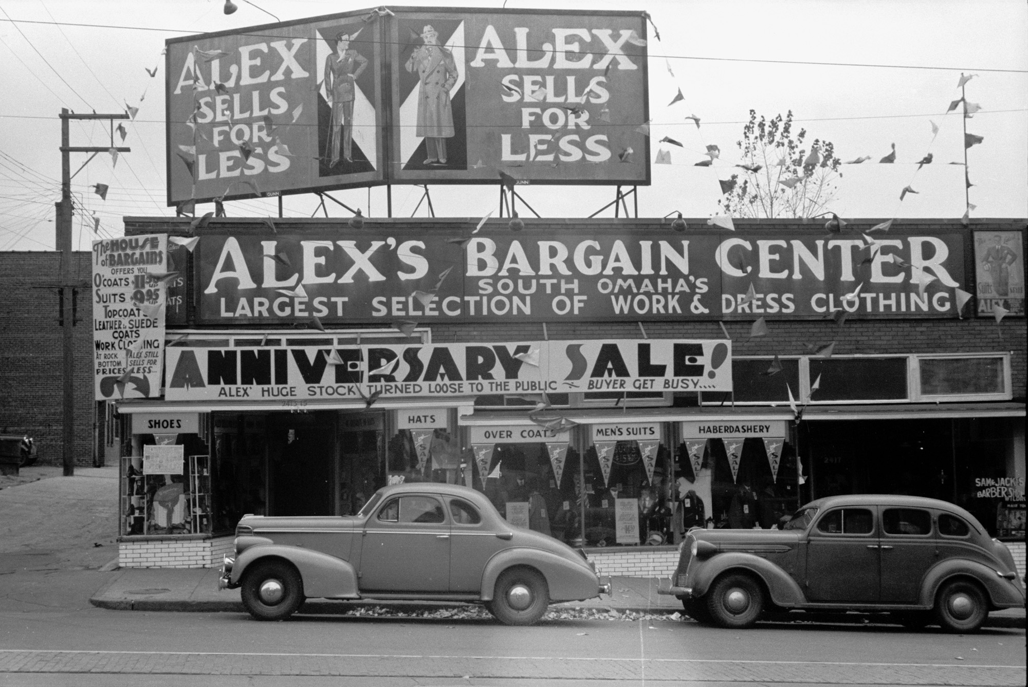 "Alex's Bargain Center, South Omaha's Largest Selection of Work and Dress Clothing." Store in Omaha, Nebraska catering to farmers. November, 1938. View full size.