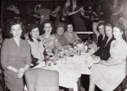 It's December 2, 1944, and my wife's Aunt Vicki, second on the left, and her girl friends (you could call women "girls" back then and get away with it) are celebrating something at the Iceland Restaurant, 1600 Broadway in New York. "Dining - Dancing - 3 Shows Nightly." The absence of men (I see just two on the dance floor) illustrates that about 13 million of them were serving in the military.
I know Aunt Vicki was writing to a sailor somewhere among those 13 million. My guess is the young lady on the left was the reason for the night out -- possibly for an engagement party -- because it appears she has slipped out of the chair closest to the camera to pose so sweetly for the shooter from Planetary Photo, 311 W. 34th St (printed on back of the one dollar photo). Also some of her friends are focusing on her. I'm happy to say today, at 89, Aunt Vicki is thriving in Delaware, has a good sense of humor and a generous nature as great as always. View full size.
(ShorpyBlog, Member Gallery)