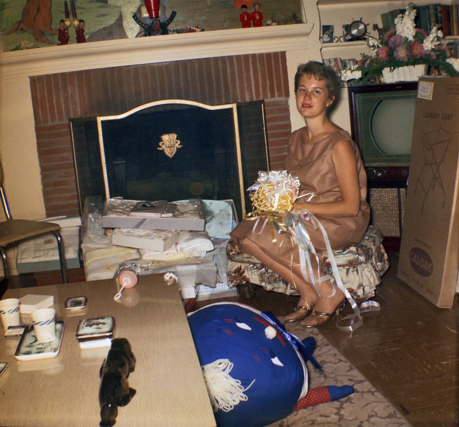 This is my grandma (who is no longer alive), pregnant with my father, making this around 1960. I'm fascinated by the mural above the fireplace and the little figures on top, but perhaps someone might know what the black thing on the table is? And, of course, the big blue thing and television are awesome. Scanned from a Kodak safety negative. View full size.