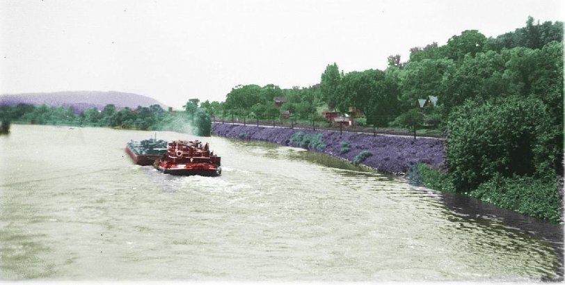 A barge heading west on the New York State Barge Canal at Ilion, NY. This photo was taken by myself in the late 50s. Originally black and white, I colorized it with Paint shop Pro. The New York Central railroad tracks follow the canal through central New York, seen here on the north shore. View full size.
