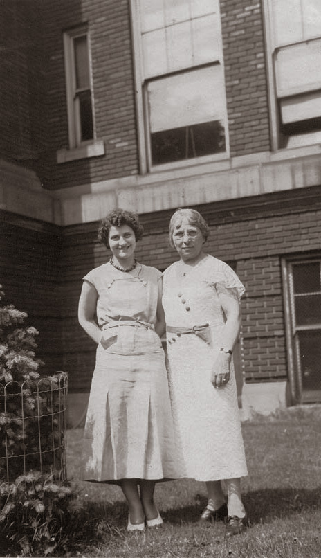 This is a photo of my great grandmother Bertha Mason (right).  The caption on the back of the photo indicates it was taken in the 1930s at the Franklin Street School in Grand Rapids, Michigan, where she was the principal.    
Bertha’s December 1945 obituary indicates she was a “former principal of several public schools in Grand Rapids.”  This includes the Franklin St. School, Lafayette Avenue School, and the South Division Avenue School.
The Franklin St. School building is still standing, but has been renamed the “Southwest Community Campus.”  It remains part of Grand Rapids Public Schools.  Using Google Maps Street View, I found the exact place this photo was taken, which pleased me greatly. View full size.
