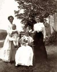 The woman in the rocker is "Big Grandma," Betsey Calista Britton (née Ware), my great-great grandmother. The woman to her left is her daughter, Martha Harriet Carpenter. To Betsey's right is her granddaughter, Mabel Carpenter Perry, who is holding her son, John Perry. The photo was taken at the Britton place in Surry, NH, in 1913 by Mabel's older brother, Fred Carpenter. Big Grandma was born on the other side of the Asheulot River and Surry Mountain in Gilsum, NH, in 1819, and died in Surry in 1917. Martha was born in 1851, and Mabel was born in 1878, both in Surry.

Steve Miller
Someplace near the crossroads of America