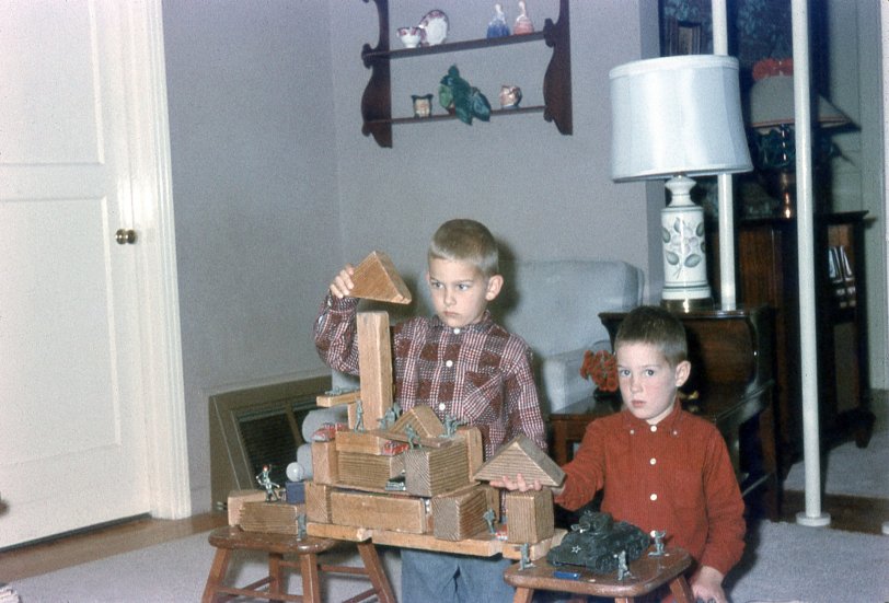 My brother and me in our San Mateo, California living room, constructing a masterpiece of military fortification. Notice the tin soldiers on the parapets, the cars &amp; trucks hidden in the crevices, and the tank parked below. View full size.
