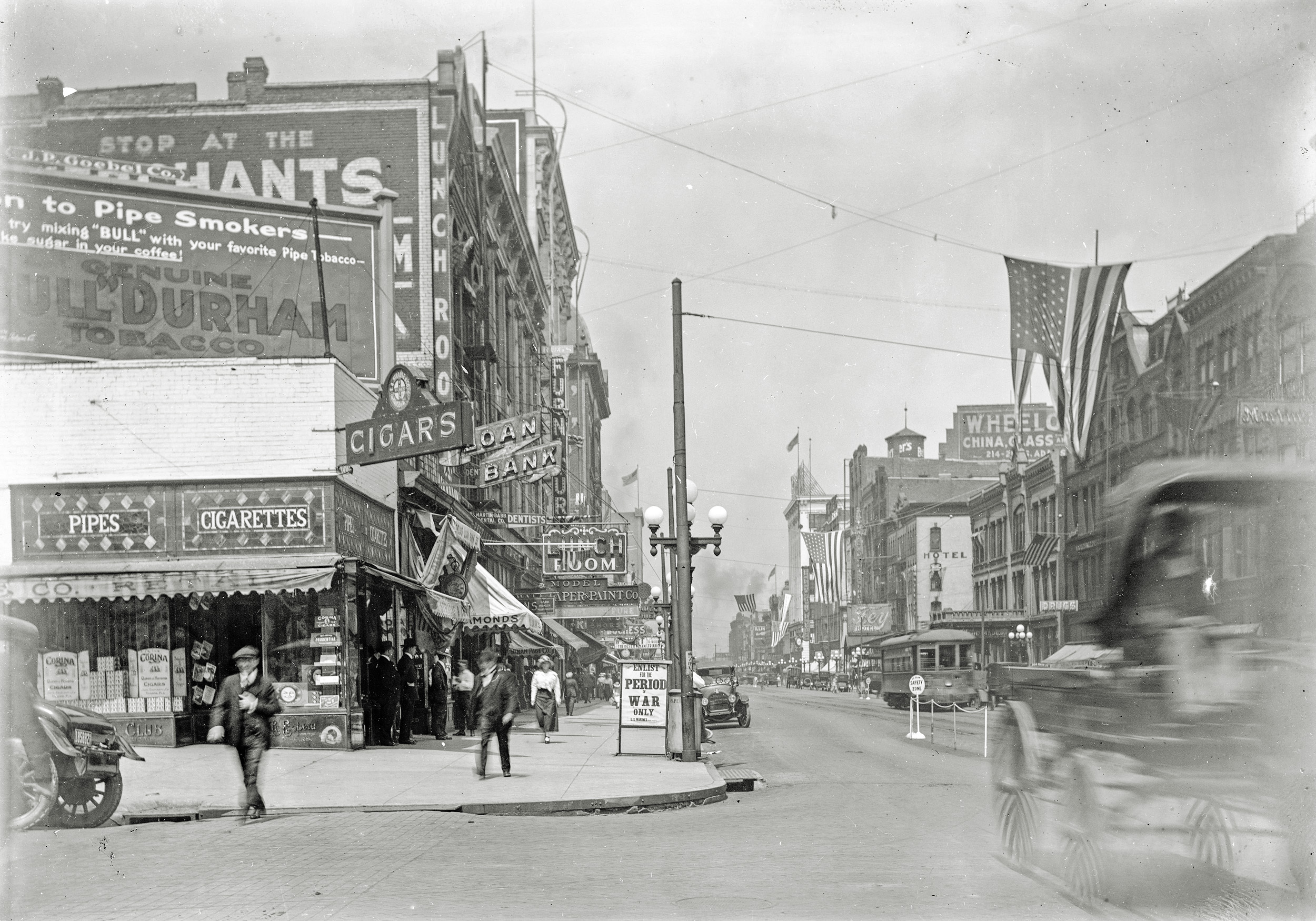 The 300 to 100 Downtown Block of South Adams, Peoria, Illinois Summer of 1917. Hotel d'Europe/Fey Hotel and Wheelock's China, Glass and Lamps in the distance. 'Enlist for the Period of War Only, US Marines'. View full size.