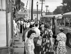 One of a half-dozen bus-related photos I got at a flea market about 20 years ago. This is somewhere in the Essex County, New Jersey area and is dated July 31, 1938 on the back. View full size.
Natty dresserthe guy in white stepping out from the shop on the left; he looks like a fish out of water.  
Public ServiceCoincidentally in the foreground of the Aussie's Google street view is a PSE&amp;G van.  Public Service Electric &amp; Gas is part of the same organization as Public Service Coordinated Transport once was.
Grade CrossingI can't offhand think where a RR grade crossing would be in Essex County.  The Lackawanna was all bridges.
I've seen that style of bus running in Summit, but that's Union Country.
Charter!For what I wonder. Was there something happening in the town on that day. Wonderful picture full of intent on the peoples faces.
Charter BusesYou can see on the middle bus that it's designated charter rather than a destination.  I suspect these folks are going to some sort of event rather than boarding the bus to go shopping or to work.  
Where were they going?This is my favorite kind of picture, because it shows a moment in the lives of a group of people. I wonder where those getting on the bus were going, that day, and what the rest were doing, too. In this case, I wonder what they were doing, three years later, when they heard about the attack on Pearl Harbor, who served in the military, and what sacrifices were made by others, who remained at home. 
&quot;If we stand here long enough&quot;"Marilyn's bound to show up eventually"
What&#039;s happening?A fascinating and vaguely disconcerting photograph. Everyone whose face is visible seems concerned, almost alarmed, about something.
Yellow Coaches?Very interesting pic. If Mr. Debold has more of buses I hope he can post them. I'm a historic bus fan and those buses look like NYC Yellow Coach model 740s. Several NYC transit lines used them. Yellow later became GM Truck &amp; Coach Div.
Aussie finds location in 1 minute80 Franklin St
Belleville, New Jersey

It&#039;s a Light Rail LineThe photo is rich in details:  That guy with the apron and the spiffy shoes &amp; socks is a tavern keeper. One can make out parts of T-A-V-E on the folded awning. What self-respecting tavern of that era would not have a Bell System pay telephone? Note also the round cover in the sidewalk close to the buildings. It's a coal chute to the basement.
Why everyone seems sort of "intense" is a good question to ponder.  There's no military draft at the date of this photo, so they are not "seeing off" draftees.  On the other hand, they might well be "seeing off" volunteer enlistees. The trouble with that theory is that some of the women have luggage! 
That RR is currently a Light Rail line known as "Newark City Subway", as it originates in a tunnel below Newark Penn Station and follows a subterranean right-of-way until it gets out of the heart of the City of Newark.
There is an obvious "dogleg" in the street in the photo. There are two doglegs in Franklin St, Belleville, NJ one of each side of the crossing! Our "Aussie" Shorpy Sleuth may indeed be correct that it is #80 Franklin. The other possibility is about #94 Franklin, looking the other way.  There's a storefront with an inset doorway at about that address.

740 minus 9leebon is oh, so close.  The buses are 1936 Yellow Coach Series 4 Model 731s.  Four series of Model 731s were built in 1935-36, all powered by a 450ci GM 6-cylinder engine, and three more series (Series 5, 5A, and 6) of the same look continued on in the Model 732 from 1936-39&mdash;the Series 5A and 6 powered by a 529ci engine.
The operator is Public Service Coordinated Transport of New Jersey, and the logo on the front of the bus can be seen in the 1940 ad for a Yellow Coach Model TDE 4001 (Transit, Diesel Electric) below.
Have to love the socks and shoes on the fellow standing in the doorway holding the newspaper.
It's nice to meet another historic bus fan (leebon that is, not the fellow with the socks).
Grade CrossingThe railroad crossing at grade in the 1938 image was the Erie Railroad's Orange branch, which eventually became part of Norfolk Southern.  The right-of-way is now shared with the Bloomfield extension of the Newark City Subway light rail line.
(ShorpyBlog, Member Gallery)