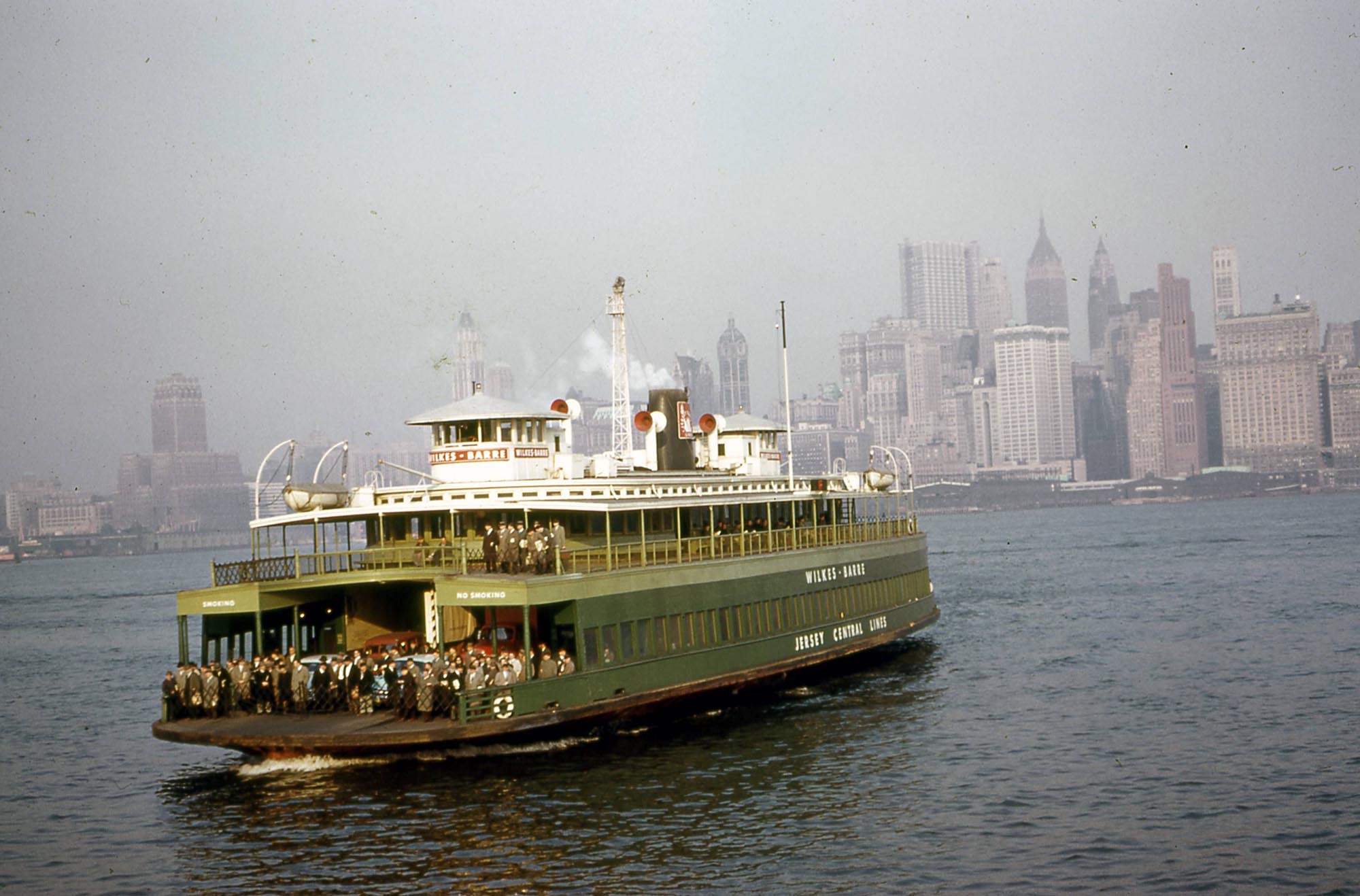 On the afternoon of March 29, 1960 I had occasion to ride the Jersey Central Railroad car ferry across the Hudson River into Manhattan. Soon after departing the Jersey City terminal I snapped this photo of the Ferry Wilkes-Barre with its patrons anxiously awaiting the boat to dock.

Not long after I took the photo, a similar shot appeared as the centerfold in the Saturday Evening Post magazine. The post captioned their photo as the "Five O'Clock Sailors," which I thought was totally appropriate.  This ferry operation is, of course, long gone from the scene. The slow ASA 10 speed of the Kodachrome film of the day seems to have taken its toll on the camera's ability to stop moving objects.  35mm Kodachrome Retina IIIc folding camera.  William D. Volkmer