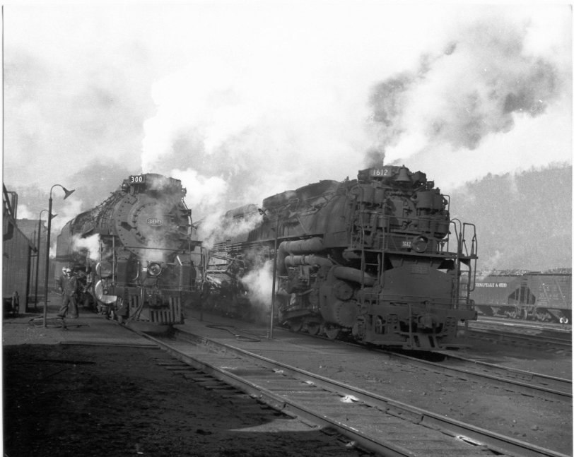 On the inbound tracks at the Hinton, W.Va., engine terminal circa late 1940s are #300, class L-2 Hudson (4-6-4), just in off a passenger run from Cincinnati or Detroit; and #1612, a 2-6-6-6 Allegheny class H-8, used primarily in push/pull coal drag service over the Appalachians to Clifton Forge, Va. The engine crew at the left brought in one of the engines; not sure which one.  C&amp;O Railway photo. View full size.
