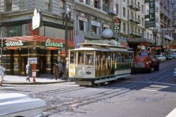 Somewhere in San Francisco circa 1958. The film is Anscochrome and the colors are well preserved. Note the Billy Graham Crusade Headquarters on the second floor!  View full size.
Baron&#039;s corner todaytterrace beat me to it. The net's pretty remarkable. I found out that the Manx Hotel is now the Villa Florence, then used Google Maps/Street View to get a picture of the actual intersection. The facing on the building above Baron's (now above Starbucks) is still the same.
View Larger Map
Make mine a doubleVery nice. Who took the picture?
Cocktail locationThis is Powell at O'Farrell. Baron's is now a Starbucks, and Lefty O'Doul's big baseball is gone, too.
Hits the SpotThat's the last really good logo for Pepsi. The next two were OK, but it's all quickly downhill after that.
The decadent &#039;70sI can't help but note that the same office that housed the "Billy Graham Crusade" in 1959 had by 1973 been transformed into the "Executive Suite Sauna &amp; Massage"! 
Locally knownFrieda Benz Oakley was a professional organist who, in the late 1940s, had an organ music studio in San Francisco.  By 1952 she had moved her studio and home to San Mateo.  As a professional in the mid-1950s, she gained a not inconsiderable reputation as a regular performer at the famous Domino Club in San Francisco, playing popular and semi-standard tunes.  She was also sought after for more public venues, such as the San Mateo Fair.  This slide shows her still playing local gigs in the late 1950s, and also tells us that Baron's had a Wurlitzer organ on the premises.
In the early 1960s she was living in Southern California and teaching in Glendale and at the Hammond Organ Studios in Pasadena.  She also was accepting invitations to play for such groups as the San Gabriel Organ Club, the Women's Association of the Congregational Church of the Chimes, and for the Los Angeles chapter of the American Theater Organ Enthusiasts&mdash;of which she was a member.  Her last public performance on record seems to be at the grand opening of the new Baldwin Piano &amp; Organ Center on Colorado Blvd. in Pasadena, in July, 1966.
What&#039;s following the cable car? Check out the red (Dodge?) truck immediately behind the cable car. It seems to have an unusual bed and a red beacon on the roof. Perhaps it's a fire truck or tow truck? 
DAVE - The photo was taken by my father. We lived just south of SF, in San Mateo, from ~ 1954 to 1961, and this is from that era. I have cases of color slides that were a part of his estate and I'll try to find the best and most interesting to scan and post. Thanks very much for hosting the venue that allows others to enjoy them! 
On The StreetIn the foreground we have what looks like the right front fender of a 1958 Buick.
On the right hand side of the street appears the taillamp and bumper of a 1957-58 Mercury.
On the left hand side of the street is a red 1947 (Third Series) - 1953 GMC cab over engine (COE) truck.
The white over green vehicle behind the GMC looks like a 1957 Ford Custom 300. The black car behind might be a 1956 Ford.
Push me pull youThe red Dodge truck following the cable car is almost certainly a repair vehicle sent out by the Municipal Railway (MUNI). Check out its oversize pushing bumper and tool boxes at rear. It appears to be assisting cable car 502, which has undergone some type of mechanical mishap and is now out of service. Witness the "Take Next Car" sign in the front window.. 
The cable car is headed for the Powell Street turntable, and if it can't be fixed there the Dodge will most likely have to push it all the way back to the car barn at Washington and Mason Streets. It will be a long push -- mostly uphill.
Cable cars were (and still are) notoriously finicky and tend to go flooey at inconvenient times. This car could have 'lost its grip,' meaning the mechanical device that grips onto the moving subsurface cable that pulls the car along. Alternately, it might have suffered some sort of brake malfunction.  Whatever the case, MUNI didn't want any riders on this trip.
All still thereSurprisingly, every building visible in the photo -- and both streetlamps -- still stand.
Photogenic CornerA few more historic photos of this street corner I found via google image search. Baron's cocktail bar was still there in 1973.  In the 1940s it was Lynch's. Jimboylan points out above that the 1940s photo is a different corner. Higher resolution images available at the linked sources: 1940s (the Tender), 1959 (roger4336),  1973 (Leroy W. Demery, Jr.). 
When the city was cool  Until the mid 60s, the fare was the same as for buses -- fifteen cents.
Alas, I admit defeatI was hoping someone would post info on the cocktail lounge names.  I found Baron's was owned and managed by S. Baron Long.  There was a vintage ashtray on line with his image in the center.  He also became owner manager of the Hawaiian Garden's Restaurant in San Jose in 1938.  They had floor shows and trained bullfrogs.  There is also a mention of Baron Long's Ship Cafe in Venice Beach but don't know if it is the same person.  However, I had to admit defeat on the sign front and center advertising someone named Benz and the last three letters of the first name "eda", I was thinking Freida, at the organ.  Guess that was one organ player who never made it big.
[Googling "Frieda Benz" + organist returns hits relating to a performer who had some California appearances during this general period. - tterrace]
HitchcockThe image has the feel of the film Vertigo.
Rail remnantsI noticed the remnants of other trackage crossing in the middle of the intersection. Was this all that was left of the O'Farrell-Jones-Hyde Street line?
Hotel ManxI stayed at the Hotel Manx for one night with a college friend in 1976; it was dingy and scary!  We were on our way to a summer of indentured servitude at a summer stock theatre in Santa Rosa.  We had just received our BAs in Drama from UC Irvine, and as college graduates we were happy to make $40 per week.  What, and give up show business?!
Lynch&#039;s isn&#039;t Baron&#039;sThe interesting 1940 photo of Lynch's and its link shows the competing California Street Cable Railway Company's Jones St. Shuttle car at the corner of O'Farrell and Jones Sts.
Lefty O&#039;Doul&#039;sLefty O'Doul's is on Geary now.  Does anyone know when it moved?
GMC Contact TruckThe contact (pusher) truck is a circa 1950 GMC not a Dodge.  The GMC logo is visible just above the grille.  A 1951 example with a set of extra lights and windshield visor is shown below.
Lefty O&#039;Doul&#039;s vs Lefty&#039;sThe only thing I know for sure is that Lefty's and Lefty O'Doul's were two different establishments. Both Lefty's Cocktail Lounge on Powell and Lefty O'Doul's Restaurant are listed in the 1960 San Francisco City Directory.  Seeing the baseball sign, you would think that both were owned by Frank O'Doul. 
Wonderful TownI was going through U.S. Navy Electronics School out on Treasure Island throughout most of the summer of 1958. Used to go on liberty in San Francisco and always thought that, if I had to live in a big city, I would choose S.F. as my first choice. I didn't leave my heart there but will always remember that city as such a vibrant place. Many happy memories.
(ShorpyBlog, Member Gallery)