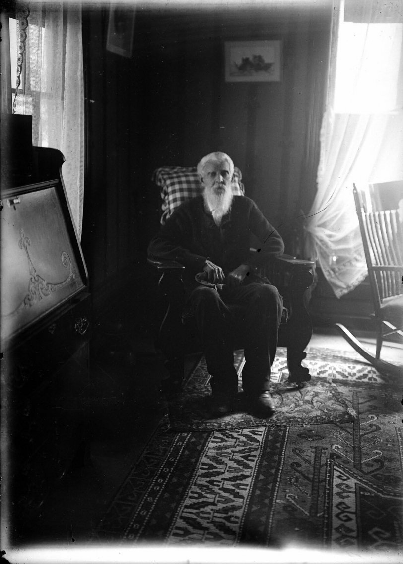 Circa 1909 photograph of an unidentified elderly gentleman relaxing in one of his two favorite chairs on North Jackson Street in Charles City, Iowa.  Taken from a 5x7 inch glass negative. View full size.
