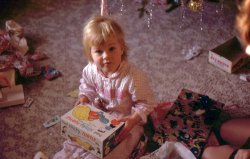 My sister Christine, probably Christmas 1968. Which was my own first Christmas, as this was the year I was born. 35mm slide. View full size.
AdorableSimply adorable.  Makes you yearn for simpler times.
The necklaceI'm about your sister's age and my sister had one of those necklaces.  It opened up and there was a tiny doll inside.  I haven't thought about that in years.  Thanks for the memory!
Next to her heart ...Nestled between the Slinky and herself, an adorable Little Kiddles Locket doll by Mattel. Hard to tell exactly which one she is, but Little Kiddles were beloved by little girls of that era.  She probably loved her Little Kiddle more than the Turtle!
Slinky Fun -- NotAh, Slinky! The original frustration toy! I could never get it to "walk" down the stairs like the commercial suggested. Inevitably I would give up and try to make standing waves instead, which always ended in a ball of twisted metal. I don't think I ever got more than 30 minutes of "fun" out of any these.  Eventually I just learned to avoid them. 
What a sweet photo!Wonderful photo! My husband and I were talking about Slinkys the other day and I told him how we never had a plain Slinky, but we had a Slinky dog, a pull toy much like the Slinky turtle. I remember we were disappointed in it. It didn't roll very well on its wheels and it stretched too long. But for some reason I chose it to take to show-and-tell in Kindergarten one week!
And thanks to Stephanie for posting the pic of the Kiddles Locket doll. I had totally forgotten about those! It bothers me though, how I can't remember if my sisters and I had them, or if friends we knew had them.
Also anti-SlinkyI have to side with KathyRo when it comes to Slinkys. They were annoying and unfun. We lived (usually) in Florida or Louisiana, so no stairs. 
I usually would spend five minutes with a Slinky doing the "pretending to juggle" activity, and then I go on to something more enjoyable like using an Etch-A-Sketch or annoying my little brother.
Have to register pro-SlinkyI went through many of the plain Slinkys because they got tangled.  On stairs you need to lift them and throw it down at the next step.  My most exciting Slinky endeavor was in high school physics class where we were studying wave propagation with 30 foot Slinkys and I got one to walk down a 20 foot stairwell in one bound.
This photo is precious and I will be remembering my daughter as she looked like this girl while I celebrate Christmas with my darling 27 year old!
Cheers all!
Name &amp; Place unknown?Could you tell us where the picture was taken. So: where were you born?
Old Town, MaineAlex, this is where I grew up in Old Town, Maine. My father still lives there. 
(ShorpyBlog, Member Gallery)