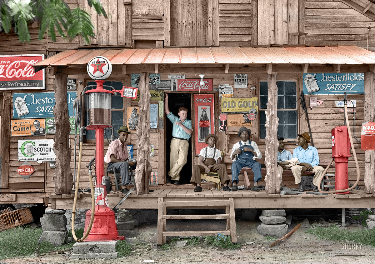 July 1939. Gordonton, North Carolina. "Country store on dirt road. Sunday afternoon. Note kerosene pump on the right and the gasoline pump on the left. Rough, unfinished timber posts have been used as supports for porch roof. Negro men sitting on the porch. Brother of store owner stands in doorway." 4x5 negative by Dorothea Lange. Click here for the original B&W photo.  View full size.
