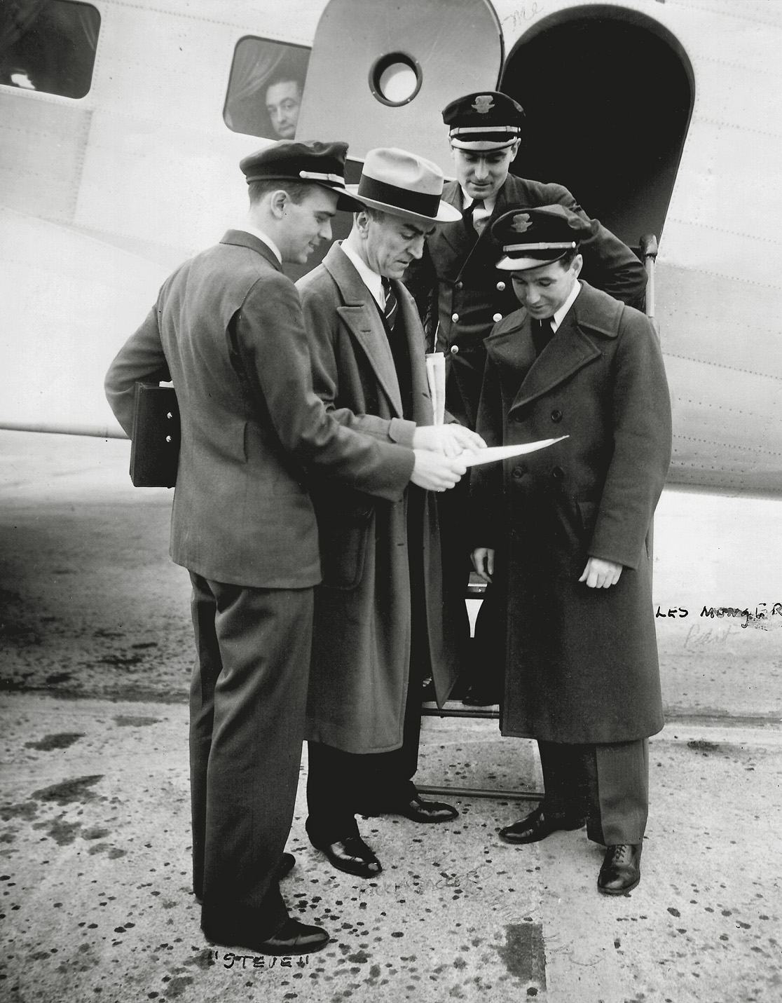Here he is again, my Gramps, Warren Erickson, at the top of the steps. This time he is in Chicago in 1934 with Captain Eddie Rickenbacker, who's wearing the fedora. This is possibly a DC-1 or DC 2, since the DC-3 entered service a couple of years later. I'm sure this shot of them all looking with interest at some paper was posed; the passenger looking out the window may be thinking "OK, let's get this show on the road." View full size.