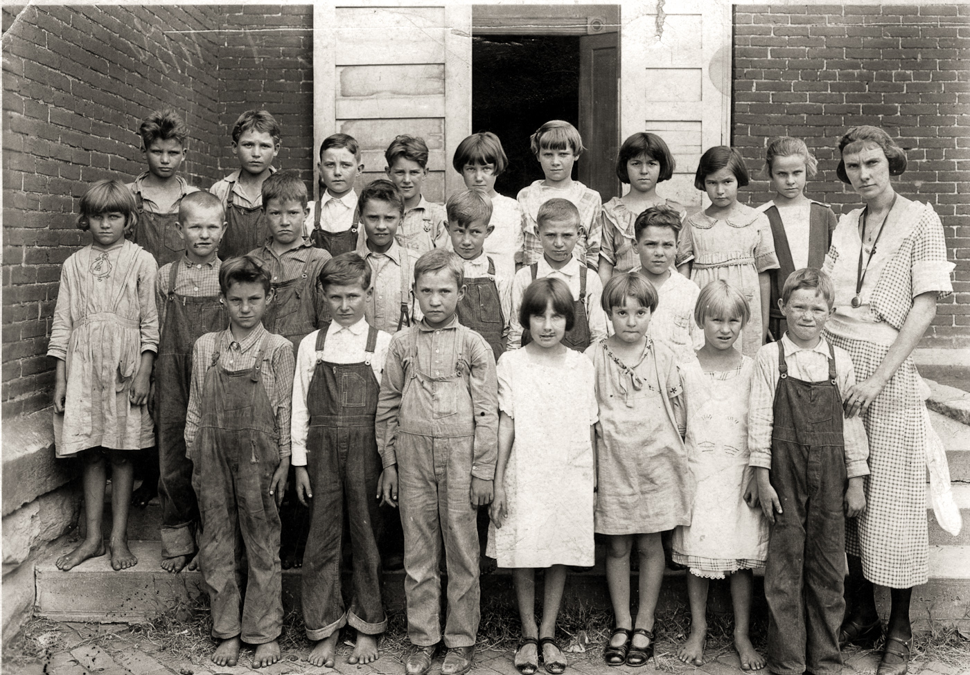 This photo has always been one of my favorites. The capture of the "real" farm life in Foster, Missouri in the 20's. My grandmother, the girl in the top row, third from the right, and her brother, front row left, are in this class. The poor children, barefoot, with dirty clothes, impetigo on their little faces and the look of the school marm are classic to me. View full size.