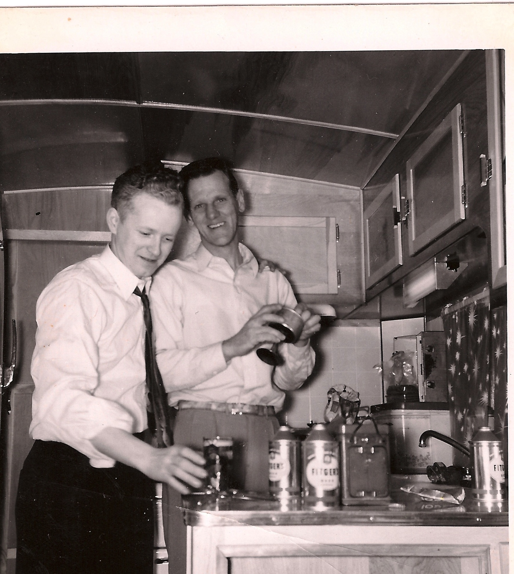 Two fellows enjoying Fitgers Beer from conetop style cans. They look to be in a trailer, camper or something similar. Why the one fellow is wearing a tie is a mystery, but he sure seems happy to down a beer. Fitgers was a large regional brewery in Duluth, MN. They lasted until 1972. The conetop cans in the picture were from around 1960 I'd guess. View full size.