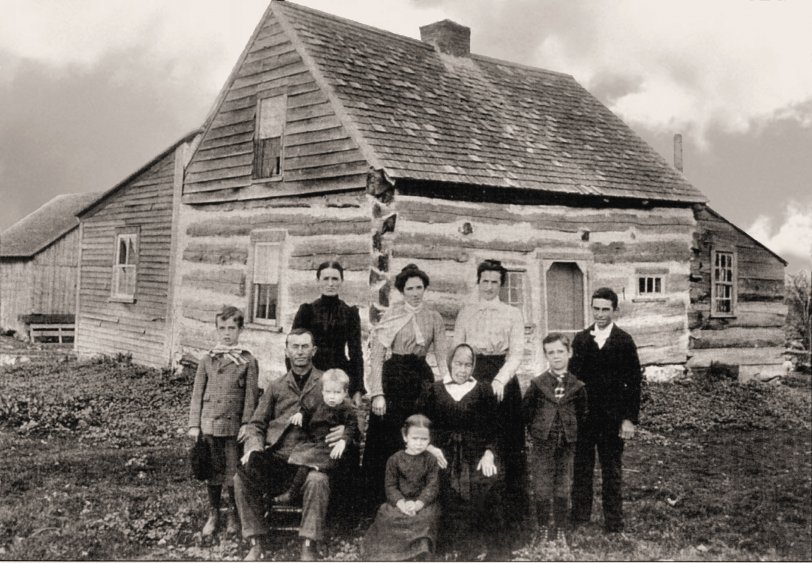 Taken about 1902:  The Foley Family poses outside their log home, built circa 1847, located on Keenan Road in the Helena area of upper New York State, Saint Lawrence County.
Standing (left to right): Herbert John Foley (born Jan 26, 1892), Herb's mother, Aunt Kate McCarthy, Miss Hurley (a dressmaker who helped get everyone ready for the picture), Herb's brother Jim and his brother Bernard
Seated: John Henry Foley (Herb's father), brother Tom seated on his knee (whose name was changed to Fr. Bernard when he was ordained a priest), sister Anne (on stool), Herb's Grandmother Foley whose husband Dennis came to this country from Ireland with his father Dennis, and his brothers, Patrick and Jeremiah.  
Herb is my grandfather.  It's odd that his mother isn't even mentioned by name and yet both the aunt and the dressmaker are named.  I guess not too many people smiled for pictures back then!
Submitted by Jack Foley of Ashburn, Virginia
