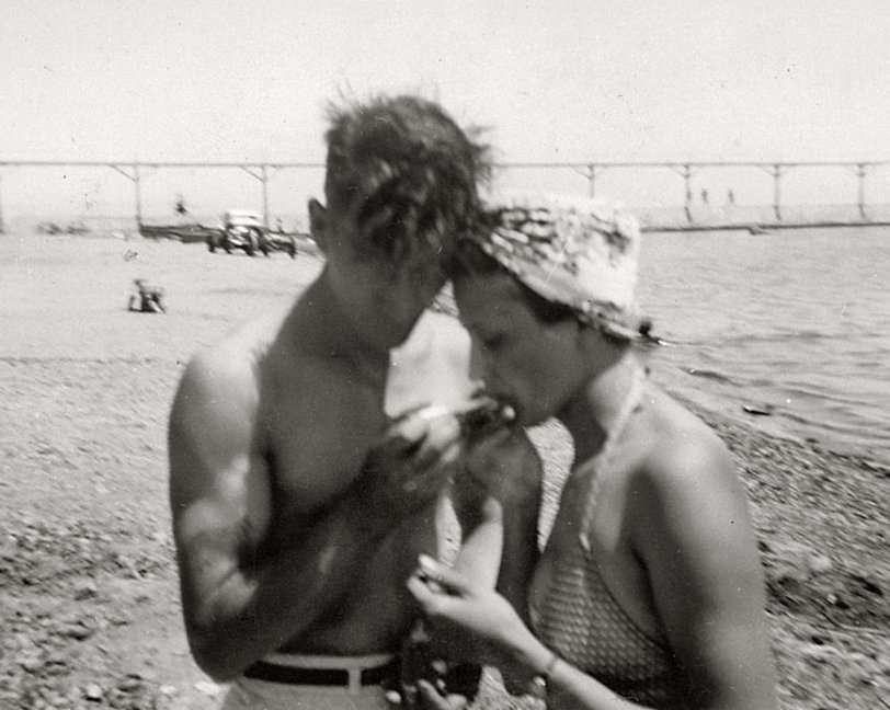 My fav candid shot of Grandma &amp; Grandpa Hughes, taken at Silver Lake, Wisconsin, 1942.  Not quite sure what they're doing (is he feeding her something or lighting her cigarette maybe?).  They're not around anymore to say &amp; daddy doesn't remember either (he was only 5 when this was taken).  Any guesses out there?  Thanx! 
