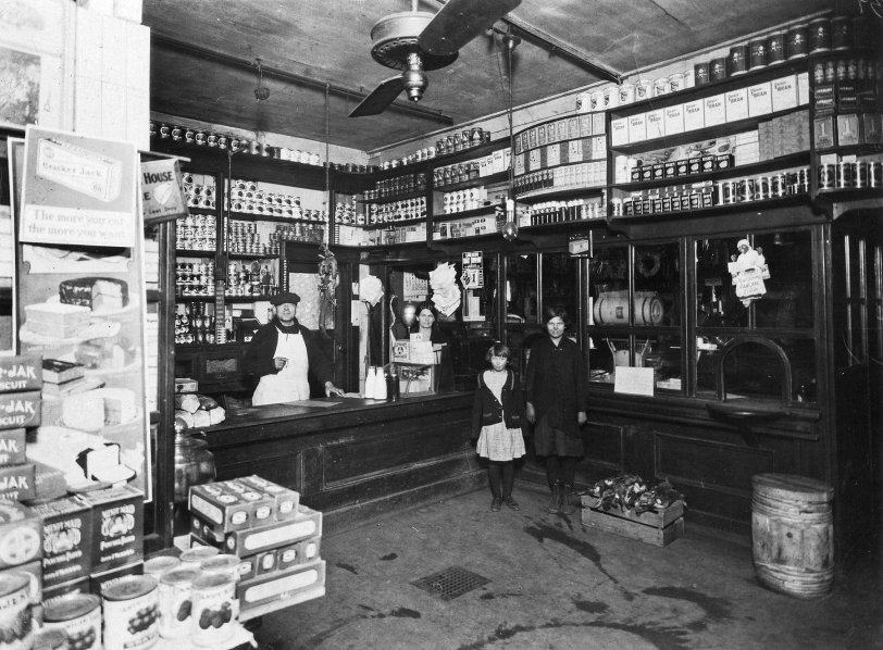 My grandparents' grocery store at 8th and Winstanley Avenue in East St. Louis IL. That intersection and neighborhood is no longer on the map having been swept away by the Interstate highway.  My grandfather and grandmother are pictured behind the counter while two unidentified patrons happily pose for the camera. Maybe they the buying that milk on the counter? Writing on the backside of the 6" X 8" print alludes to the photo having been taken in 1914.  Everyone appears to be dressed warmly.  It may have been November 30 based on the calendar hanging in the background. Also seen here in 1920. View full size.
