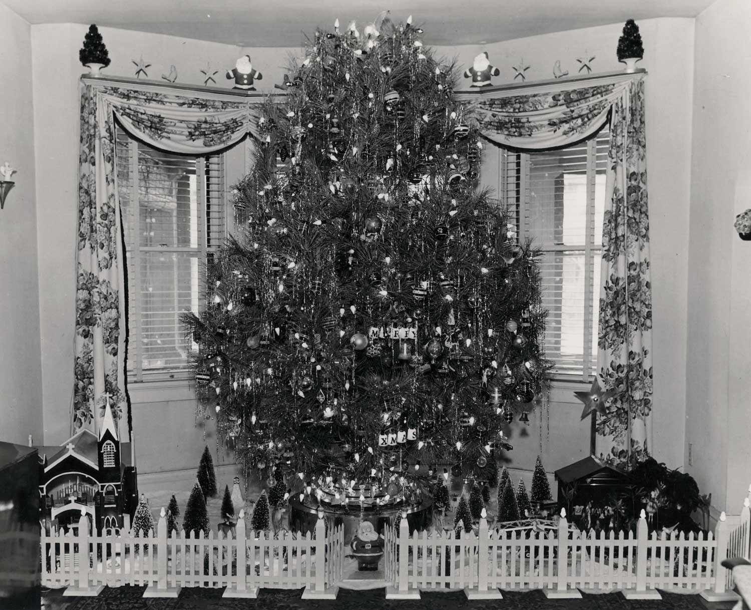 This is my Grandfather's Christmas tree mounted in his homemade rotating stand. The photo was taken in Gary Indiana about 1950. There are slip rings in the base which allow 30 combinations of lighting on the tree as it turns. I inherited the base and still use it every year with a real tree. View full size.