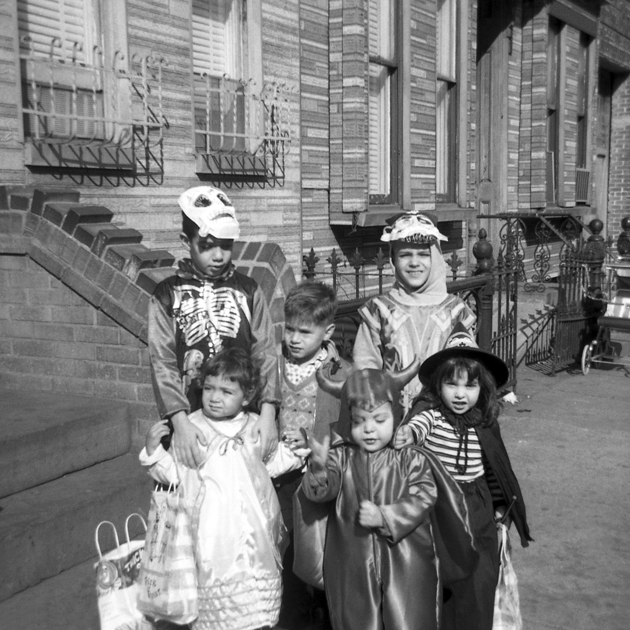 My sister (the witch), myself (devil), and several neighbors get all costumed up to go trick-or-treating on Hart Street in Brooklyn in 1965. Scanned from a B&W negative. View full size.