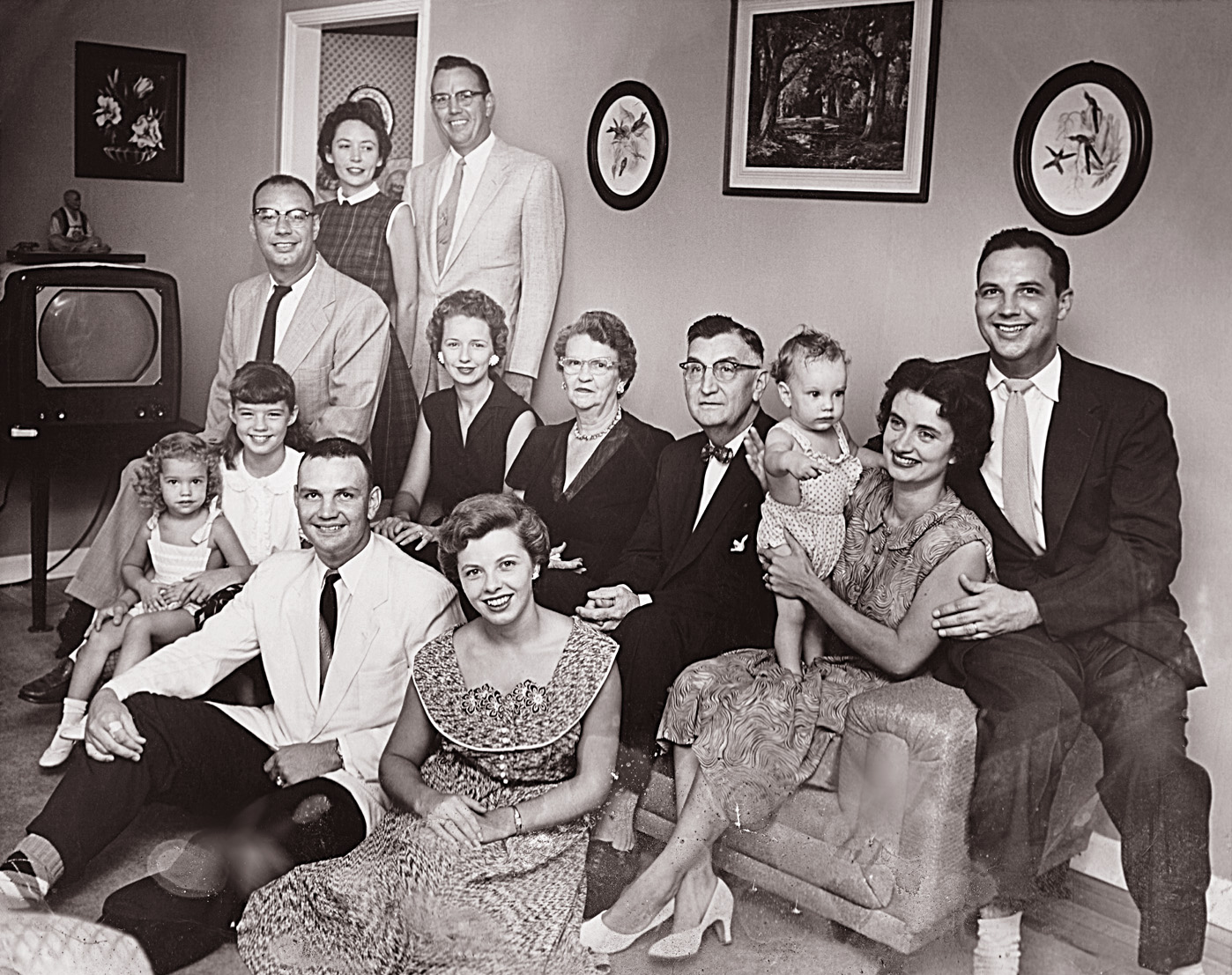 The Harrison family, August 1955, Huntington, West Va., taken in the grandparents' house (note that the TV has the pride of place).  I'm the one perched on Mom's knee. View full size.
