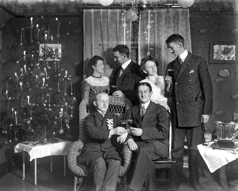 Christmas with my grandparents in Buffalo, New York.  They are the couple on the right.  Grandmother emigrated to the U.S. in 1909. This is likely from one of their first Christmases in America as the image comes from a glass negative. There are a couple dozen glass negatives so it would appear that Granddad moved to film stock by the Teens.

The other folks in the image are unknown by name but appear in multiple negatives from this time period. I'm fairly positive that none are relatives -- more likely other immigrant friends from Germany or acquaintances met in the U.S.

The "Charlie Brown" tree is decorated with nearly two dozen burning candles! The chandelier appears to be gas with flow regulators on each of the arms going to the globes. View full size.