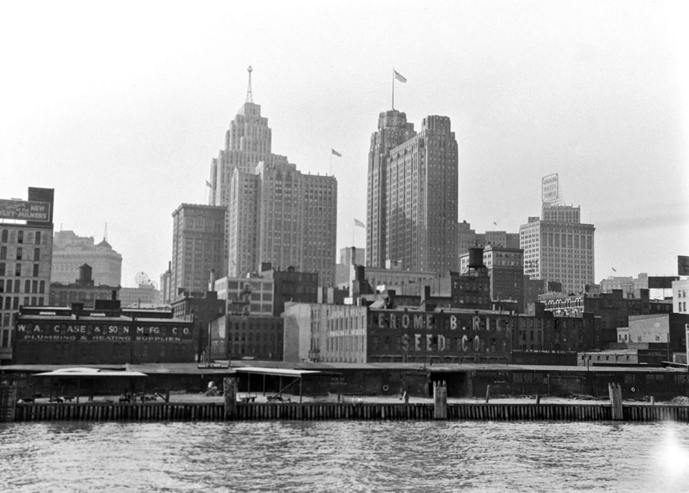 Downtown Detroit as seen from the Detroit River.  The tall building flying the American flag is the Guardian building (built 1928-29).  The Guardian building still stands and is the headquarters for Wayne County, Michigan. View full size.