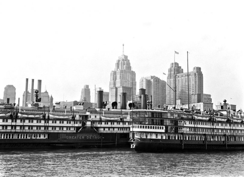 Two passenger boats sit on the Detroit River near downtown Detroit, MI. They likely traveled across Lake Erie between Detroit and Buffalo, NY. The Guardian building is seen flying the American flag on its roof. View full size.
