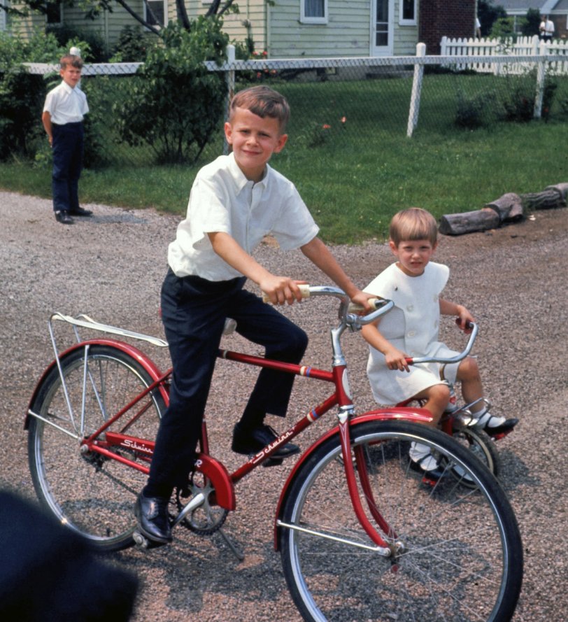Indianapolis, 1968. My brother Dan on his Schwinn along with sister Beth on her trike, in the alley next to our house.  Our cousin David is back by the fence.  We were all dressed up for our youngest brother's Baptism. View full size.
