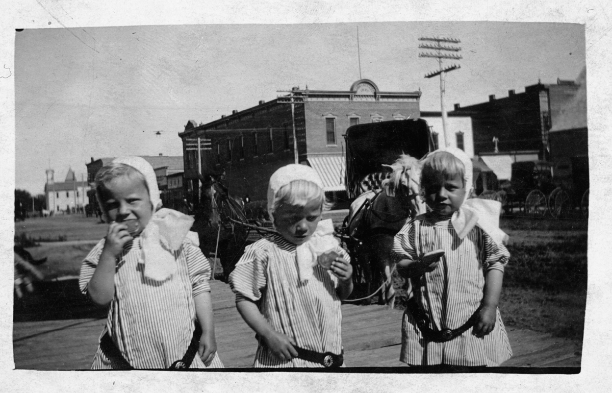My grandfather Harold Jensen along with his brother and sister, Holger and Hilga, were born on October 19, 1909. Multiple births were a big deal back then and the triplets were minor celebrities in and around their hometown of Cozad, NE, having their pictures taken many times during their childhoods. All three lived well into adulthood. They are gone now, but I'd like to wish them all a happy 99th birthday!

I find this photo not only interesting because of the main subjects, but because I suspect they were 3 or 4 years old when this photo was taken, and you can see that the main mode of transportation was still horse and buggy - except for what appears to be a biplane just above the head of the child on the left.

The image I scanned from, although very sharp is only 3¾ x 2¼ inches on the front of a 5½ x 3½ "postcard." I sure wish I had the glass negative for it! I just know there's a lot of lost detail! 

Here is a closeup of what I believe is a biplane.