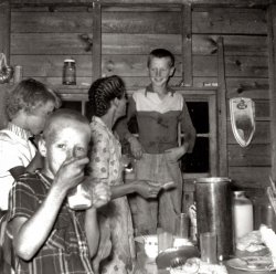July 1955 - Cordova, Alabama. My grandmother, Bessie Johnson, makes homemade ice cream for the kids. That's my dad, Sam Johnson, grinning from ear to ear standing on the chair in the background. That's uncle Gene in the front and Aunt Betty on the far left.
(ShorpyBlog, Member Gallery)