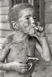 Leatherwood, Kentucky, 1964. "Boy covered by dirt smoking cigarette with one hand, holding can of tobacco in other." The tobacco-loving Cornett boys started early. Gedney Photographs Collection, Duke University.  View full size.