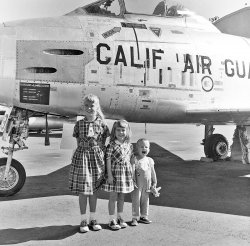 Way back in 1958 the Clark kids were visiting the California Air National Guard Base at Van Nuys. View full size.
The wild oneI get the impression that Junior was the kind who required the full force of two big sisters and a jet fighter to be kept in check.
F-86This looks like an F-86 Sabre, common in Air Guard units of the era. I can't see the nose well enough to tell if it's a F-86D/K/L variant.
Nice.Nice photo of a local landmark.
Not all F-86H models have 2 guns on each sideThe F-86H-5-NH has 2 guns per side as shown in this photo.  So does the F-86H-10-NH.  But the F-86H-1-NH has 3 per side.
F-86?Not sure it is an F-86. The F-86 had six 50 cal guns, not 4. And the wing seems to be further back than on an F-86. But I can not think of another plane it could be.
F-86HIf I am correct it' is of the F-86H variant. You can see the model number right above the serial number. 473 of that model were built and also was capable of carrying nuclear weapons and had a low  altitude bombing system on board as well (LABS).
Looks like junior was doing his F-86 fly-by roar.
Jeff
F-86HThat is an F-86H, the last Sabre variant before the radome-equipped, rocket-carrying, gunless F-86D.  Four 20mm cannons in place of the earlier Korean-war Sabre's six 50-calibre machine guns.  
F-86HFolks, this is an F-86H.  The -H was the last model of the F-86 Sabrejet series as delivered to the U.S. Air Force.  It had four 20mm cannon instead of the six .50 cal Browning machine guns that were installed in earlier models.  The F-86H served briefly in active USAF service (1953 'till about 1957), after which they soldiered on with some Air National Guard units as late as 1971.  More info and many photos are just a google search away.  
Four Gun SabresThe F-86H (-5 and -10, the final versions of the F-86) had four M-39 20mm cannon. I believe those were the only ones that did.
It is definitely an F-86F-86H-5-NH, to be exact.
Serial Number is 52-5749, making it part of the first batch of 86-H5s built at North American's Columbus, OH plant.
It&#039;s an &quot;H&quot;This is a North American F-86H, of which 475 copies were made, the last H rolled off the assembly line in 1955. I don't know why there are only two openings for the guns since the production models had three per side.
The H, you sayThe upcoming Shorpy Olympics will pit the Car Identifiers against the Plane Spotters.
F-86H-5-NH for sureItsa_me_Mario has it right. A great site for checking military aircraft serial numbers is
http://www.joebaugher.com/
If you follow his links to 1952 Air Force serial numbers you'll see "52-5729/5753 - North American F-86H-5-NH Sabre". He doesn't list the ultimate disposition of this particular aircraft, but several with serial numbers near it were converted to drones (QF-86H). 
One source says the Navy acquired QF-86Hs for missile tests at China Lake California (one or two valleys over from Death Valley) in the late fifties and sixties. So this one may have wound up on the receiving end of tests of the Navy's formidable Sidewinder heat-seeking air-to-air missile, developed at China Lake.
Case where everyone is rightfrom http://www.nationalmuseum.af.mil/factsheets/factsheet.asp?id=2299
"TECHNICAL NOTES:
Armament: Four M-39 20mm cannon (Blocks 5 and 10; last 360 aircraft built) or six .50-cal. machine guns (Block 1; 113 aircraft built); "
Dress spotterI don't know anything about planes, but I think I had one of these dresses in 1958.  It was blue and purple plaid cotton, from the Sears on Main St. in Santa Ana, CA.  Does this ring a bell with anyone?
R.C.A.F. SabresCanada built Sabres from 1950-1958, they were called CL-13
there were 1,815 built, 6 versions(marks) and were originally planned from the F-86A. Thirteen other countries flew the F-86, most passed down.
The oldest girlLooks to be the same age as my mom in '58, which was 12. 
Dress Spotter 2I'm sure it is red, white, blue and it was sold at Macy's for $8.99. It has a 1/2 inch hem and buttoned in the back. The $10.51 model had a zipper. 
Van Nuys ANG TodayJust an empty lot adjacent to the Van Nuys airport.
The barracks and administrative buildings were torn down about a year ago.
View Larger Map
(ShorpyBlog, Member Gallery)