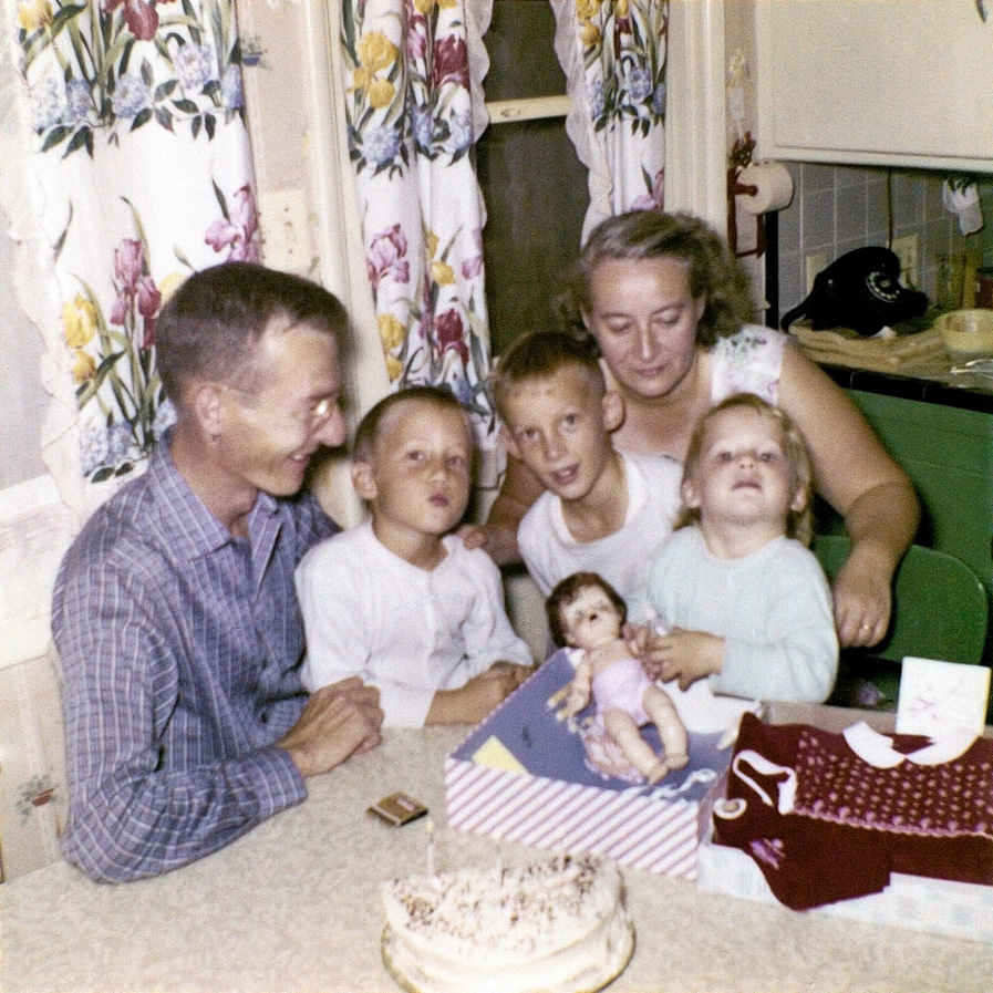 This picture is at our kitchen table in Upland, California in 1958. My sister Linda is showing her Tiny Tears doll on her third birthday. Notice only half a cake with 3 candles. My mom gave the other 1/2 cake to an 80-some year old named Gertrude. She lived across the alley. She could not cook, so my mom would have us kids take over part of our dinner to her many times a week. Mom had a heart of gold. View full size.