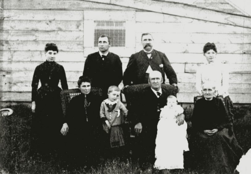 This picture was taken about 1888, I believe in South Dakota.
Seated left to right: Sophronia Maria Lucas (née Lowe) with her grandson Carroll Mayne Lucas; Parker Lucas; the baby on his lap is Parker Vincent Lucas, his great-grandson.  The elderly lady is Sylvia Fulton, Parker's second wife.
Standing in the back: the gent staring off into the distance is Aaron Briney Lucas Sr. and the hefty gentleman with the mustache is William Vincent Lucas, Aaron's dad.
I do not know who the two women are standing on either side of the men.  

